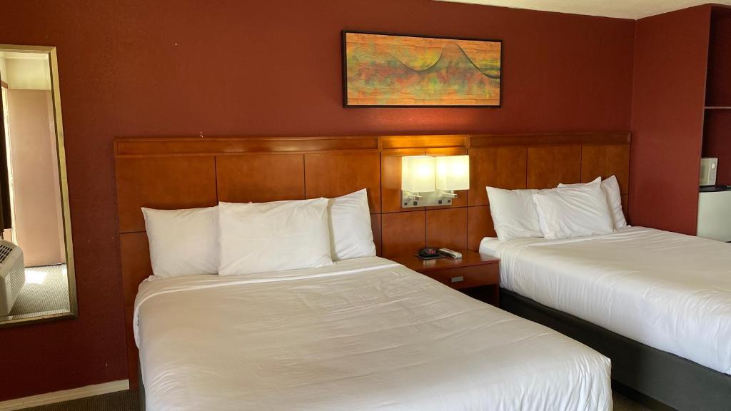 2 Betten in einem Hotelzimmer mit weißer Bettwäsche in der Unterkunft Lakeshore Inn Water Front in Moses Lake