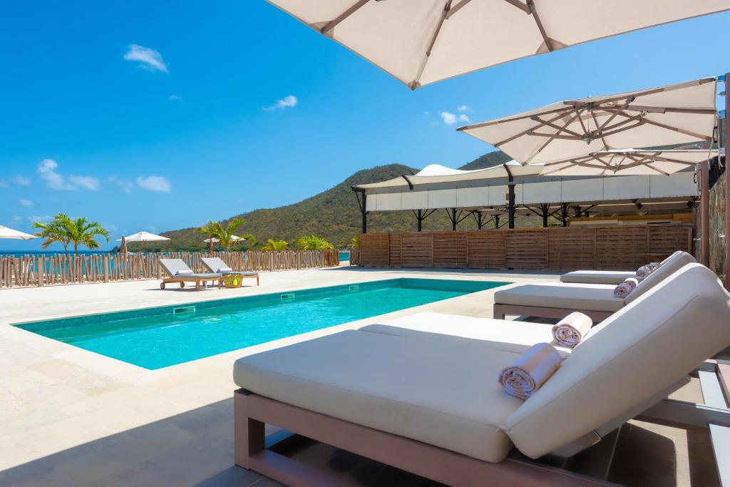 a pool with chaise lounge chairs and an umbrella at Le Domaine Anse Marcel Beach Resort in Anse Marcel 