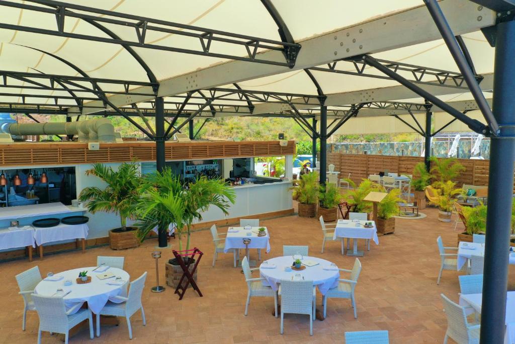 a restaurant with white tables and white chairs at Le Domaine Anse Marcel Beach Resort in Anse Marcel 