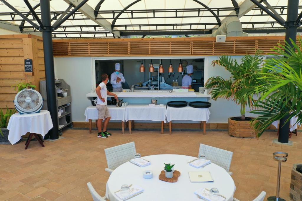 a woman standing in a room with tables and chairs at Le Domaine Anse Marcel Beach Resort in Anse Marcel 