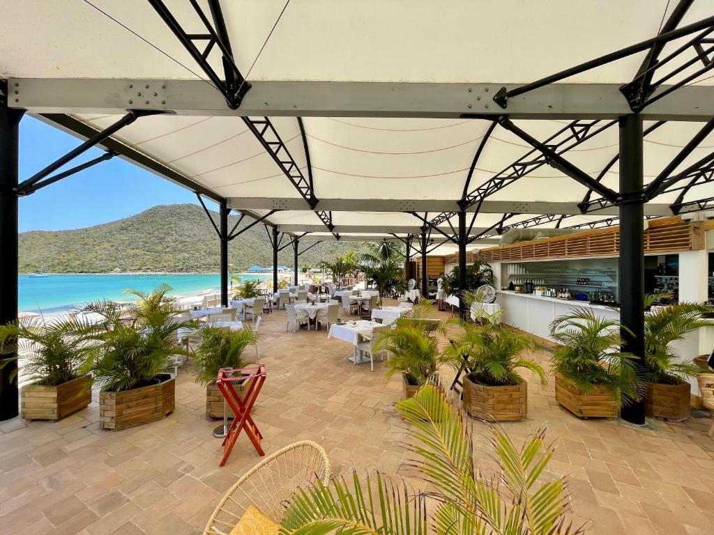 a restaurant with tables and chairs and a beach at Le Domaine Anse Marcel Beach Resort in Anse Marcel 