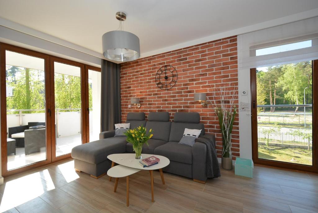 uma sala de estar com um sofá e uma parede de tijolos em Apartment Premium Wood Baltic Park - 58m2, 3 pokoje em Stegna