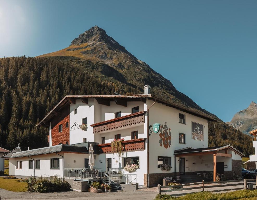 a white building with a mountain in the background at Hotel Alpina in Galtür