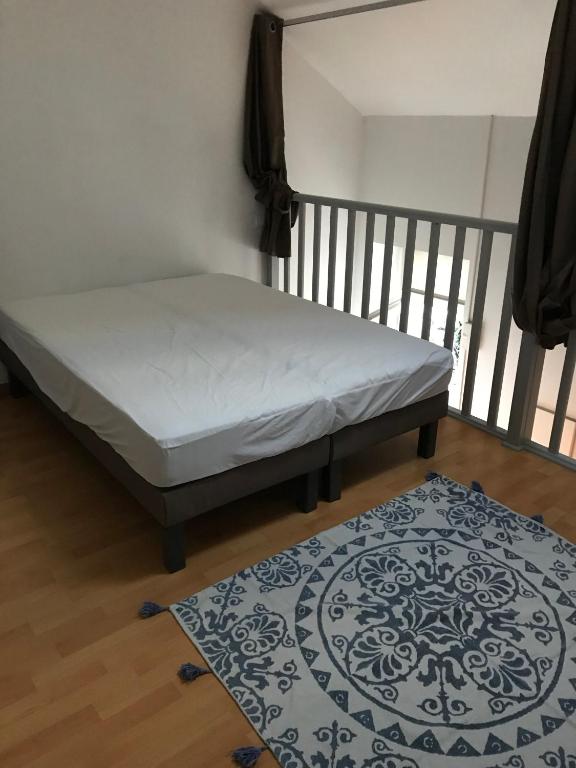 - un lit dans une chambre avec un tapis au sol dans l'établissement L'échoppe Rochelaise, à La Rochelle