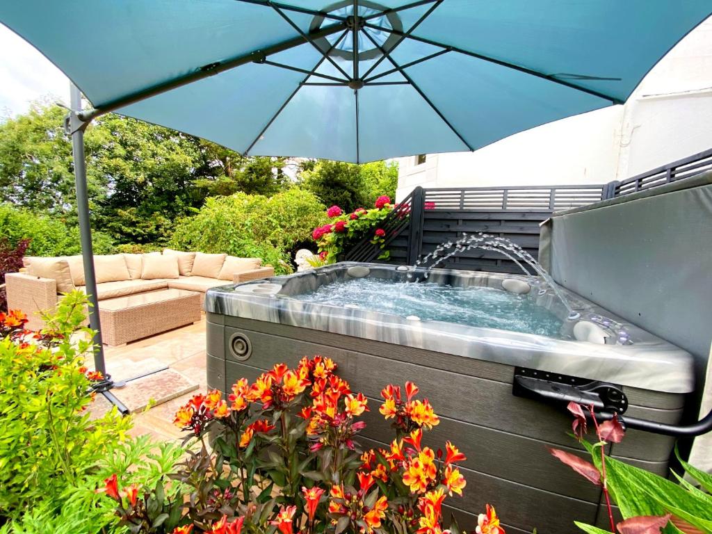 a hot tub in a garden with an umbrella at The Town House at Muntham- Luxury Holiday Home with Hot Tub in Torquay