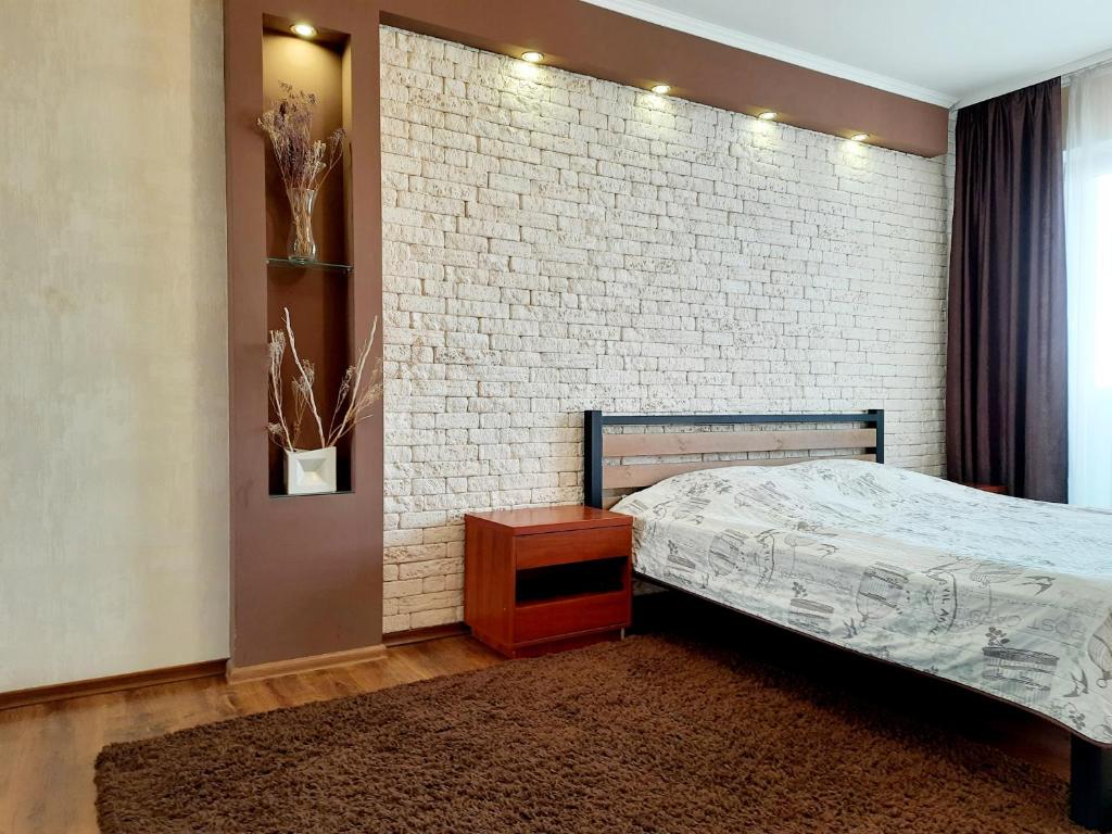 a bedroom with a bed and a brick wall at Староярмаркова с видом на парк и реку in Kryvyi Rih