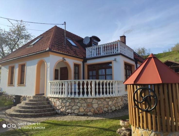 una pequeña casa blanca con una valla delante en Erzsébet Vendégház, en Csesznek