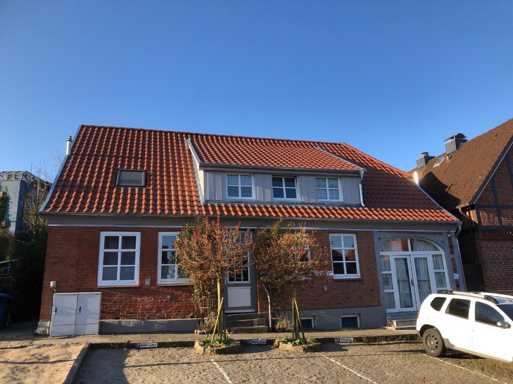 una casa de techo rojo con un coche blanco aparcado delante en Kalkberg Ferienwohnungen, en Bad Segeberg