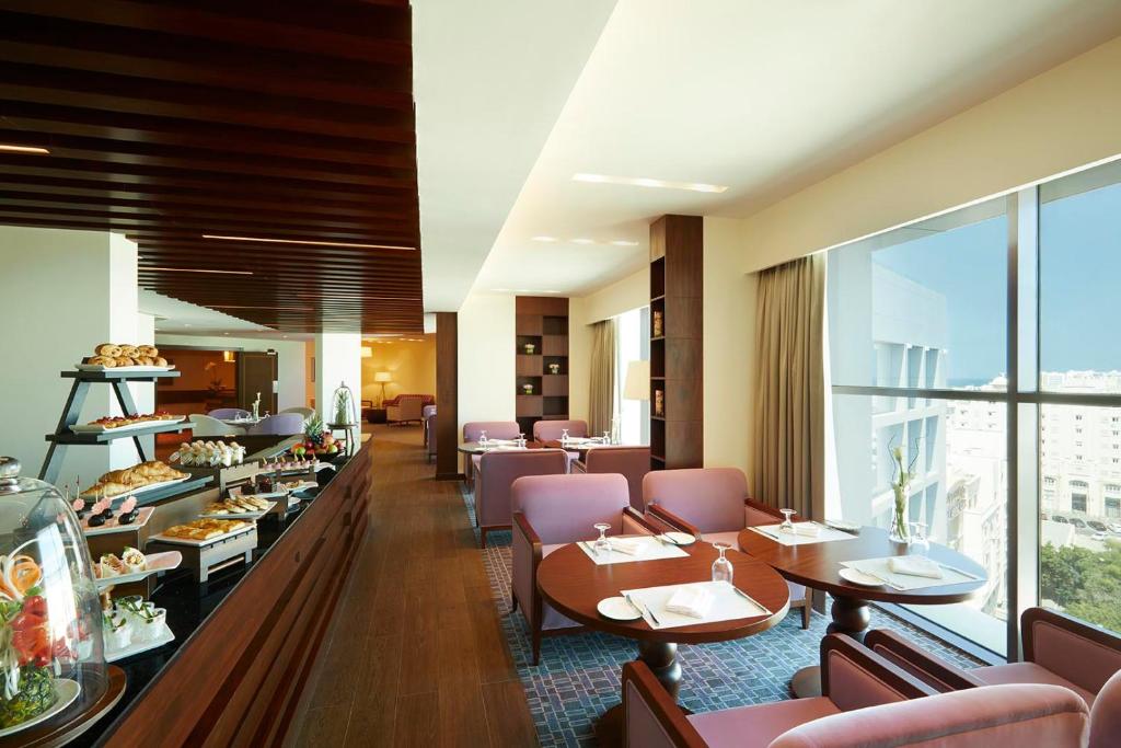a restaurant with tables and chairs and a cafeteria at Royal Tulip Muscat in Muscat