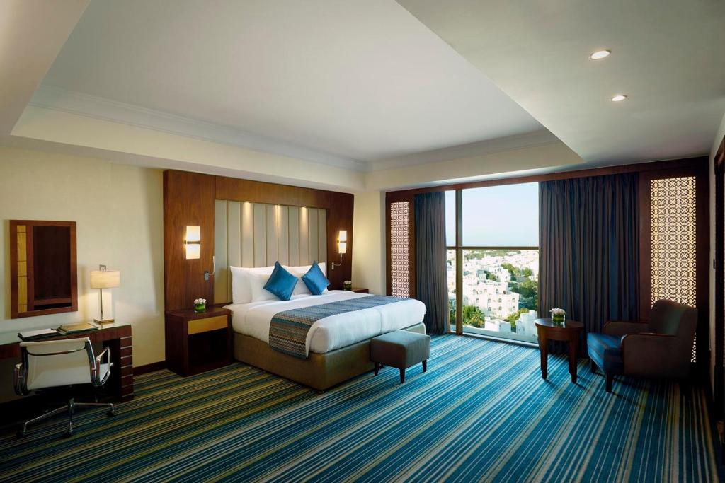 a hotel room with a bed and a large window at Royal Tulip Muscat in Muscat