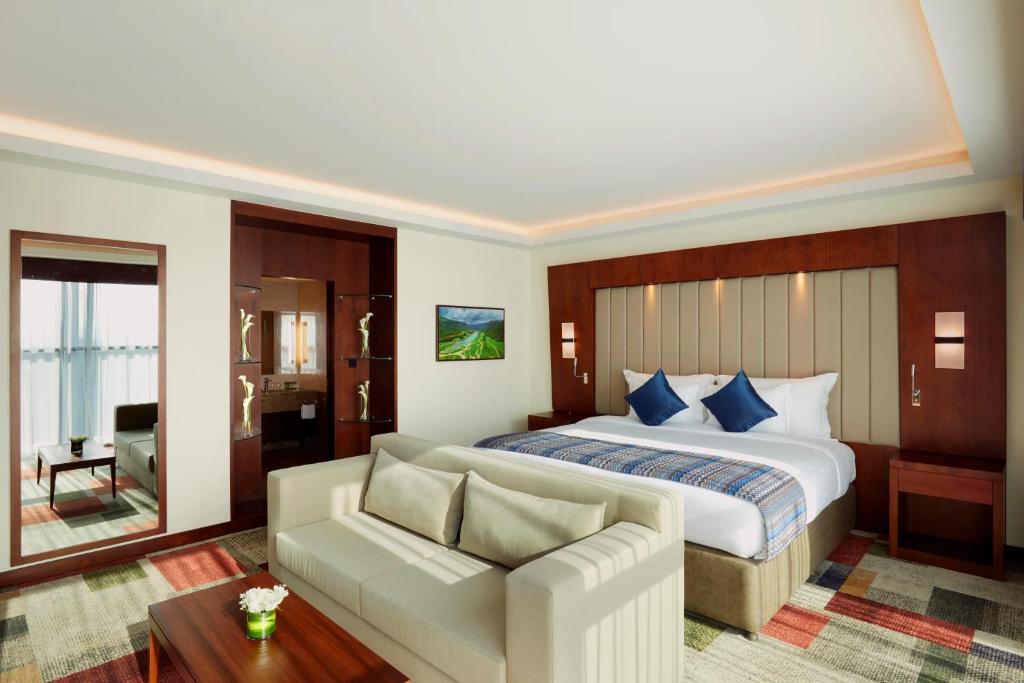 a hotel room with a bed and a couch at Royal Tulip Muscat in Muscat