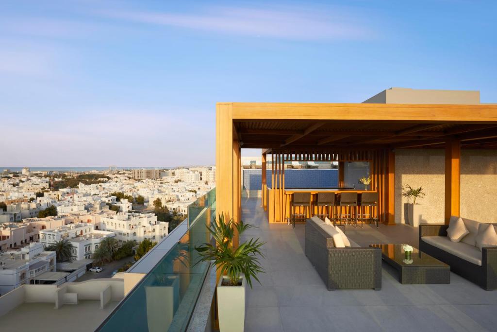 a balcony with furniture and a view of a city at Royal Tulip Muscat in Muscat