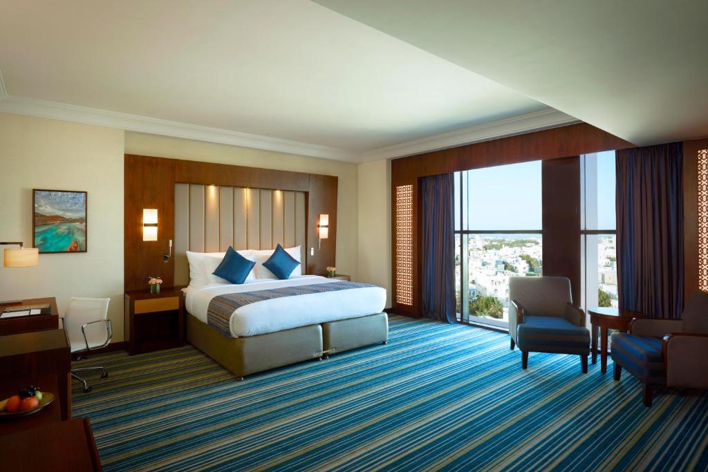 a hotel room with a bed and a desk and chair at Royal Tulip Muscat in Muscat