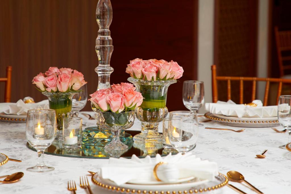 a table with pink flowers in vases on it at Royal Tulip Muscat in Muscat