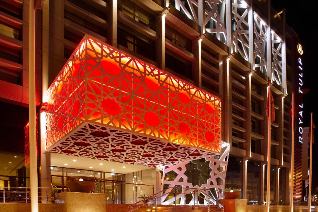 a building with a lit up sign in front of it at Royal Tulip Muscat in Muscat