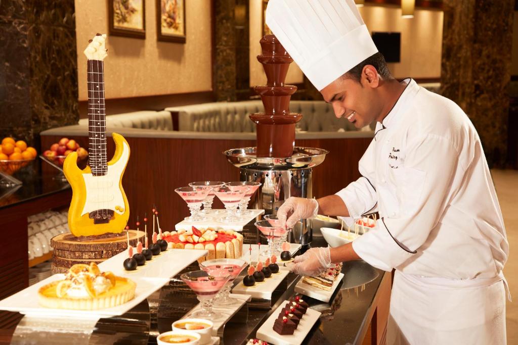 a chef preparing a buffet of food in a restaurant at Royal Tulip Muscat in Muscat