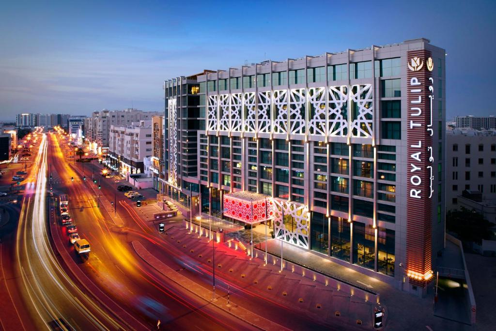 a large building on a city street at night at Royal Tulip Muscat in Muscat