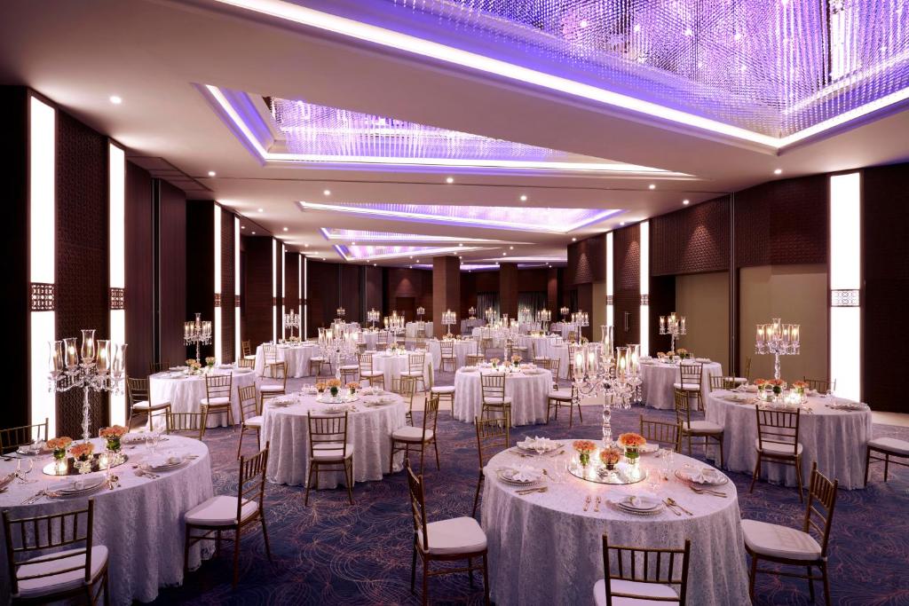 a banquet hall with white tables and chairs at Royal Tulip Muscat in Muscat