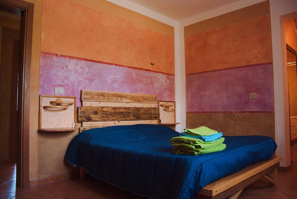 a bedroom with a bed with blue sheets and a wall at B&B Terra e Paglia in SantʼAnna