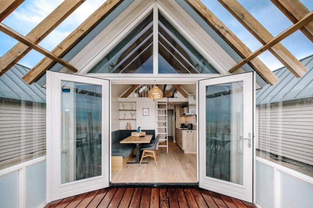 una extensión de cristal a una casa pequeña con mesa de comedor en Thalassa Beach Houses, en Zandvoort