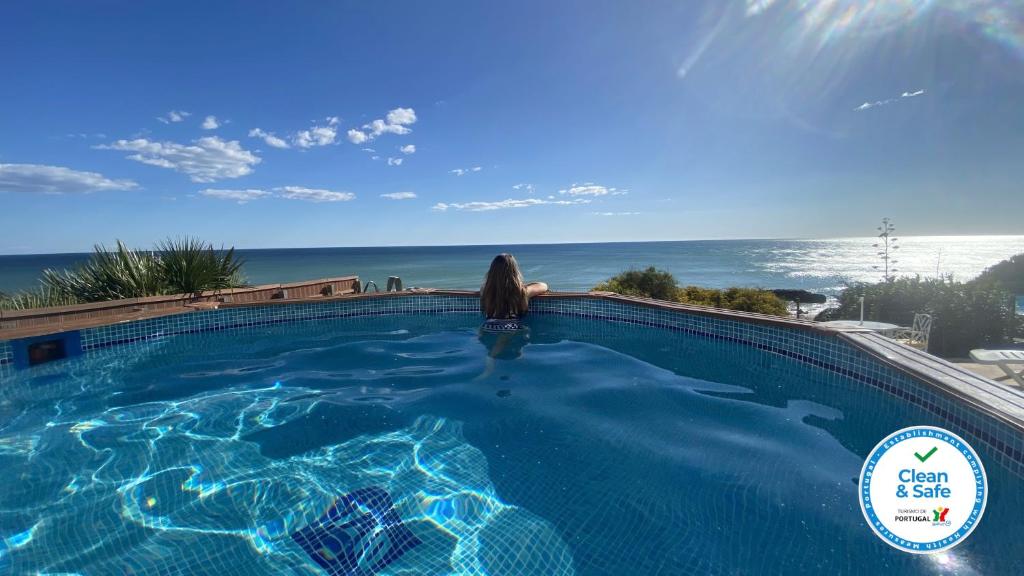 kobieta siedząca w basenie patrząca na ocean w obiekcie Beira Mar by Check-in Portugal w Albufeirze