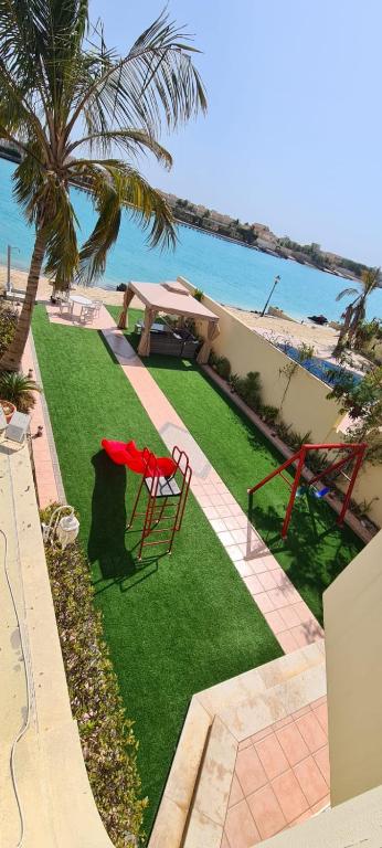 a lawn with a table and chairs and the ocean at درة العروس كورال بيتش فيلا in Durat Alarous