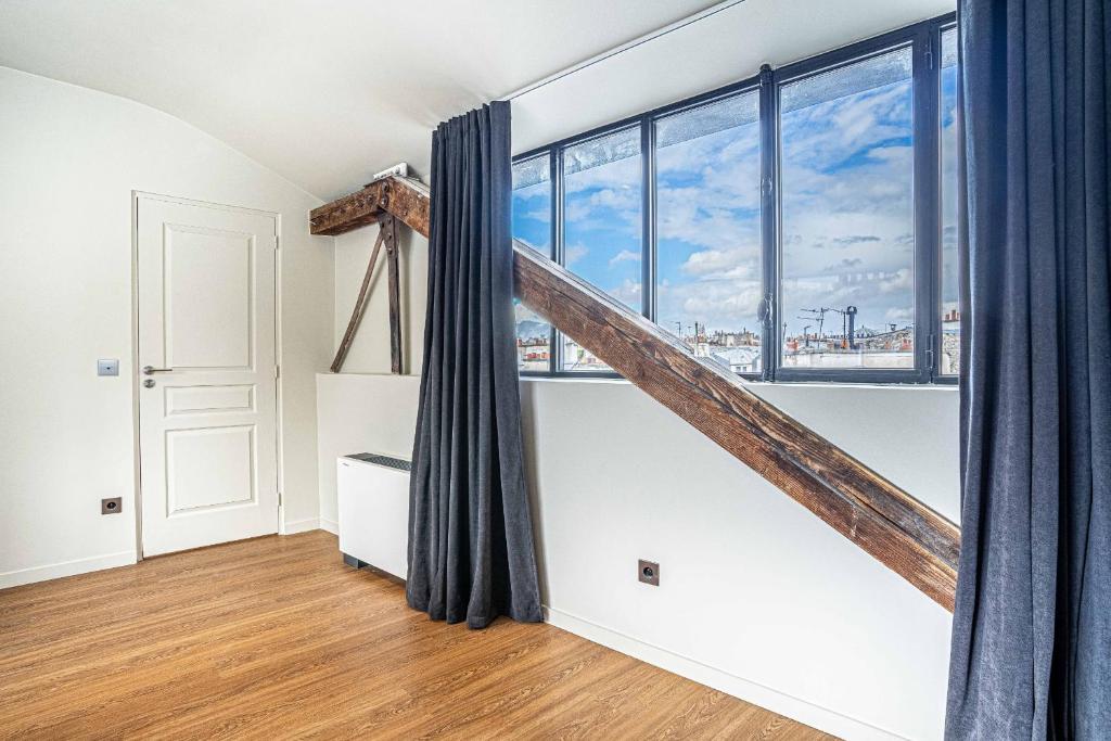 a room with a staircase and large windows at 135 - Urban Five Star Apartment in Center of Paris in Paris