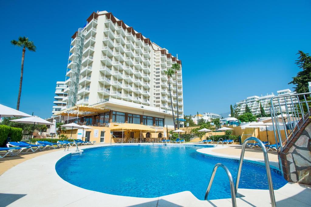 a swimming pool in front of a tall building at Hotel Monarque Torreblanca in Fuengirola