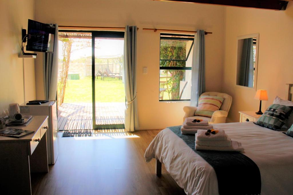 a bedroom with a bed and a sliding glass door at Tortoise Trail Lodge in Langebaan