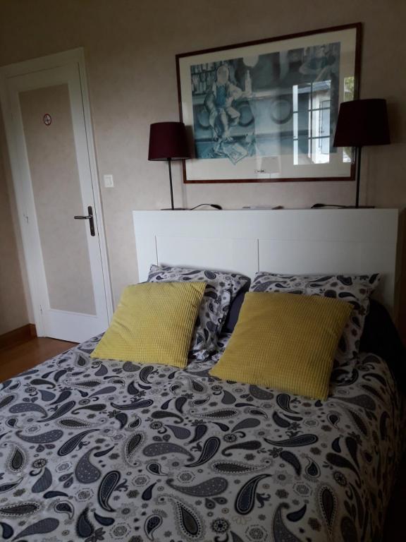 um quarto com uma cama com duas almofadas amarelas em Chambre dans jolie demeure em Gouesnou