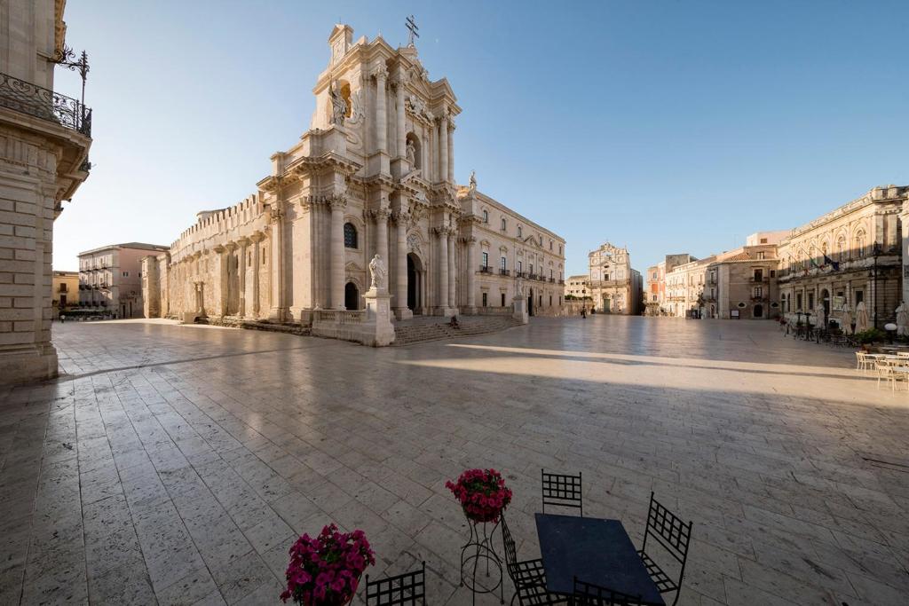 un gran edificio con una torre de reloj en un patio en Ortigia Loft Via Malta, 22, en Siracusa