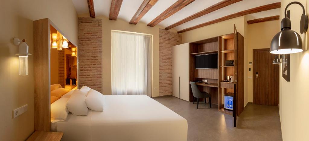 a bedroom with a large white bed and a desk at SH Suite Palace in Valencia