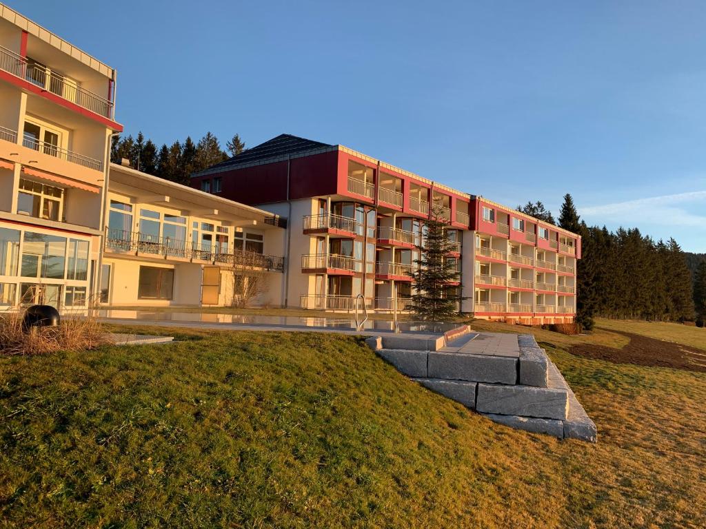 ein großes Gebäude auf einem grasbewachsenen Hügel neben einem Gebäude in der Unterkunft Hotel Saigerhöh Wellness Spa Golf Wandern über dem Titisee in Lenzkirch