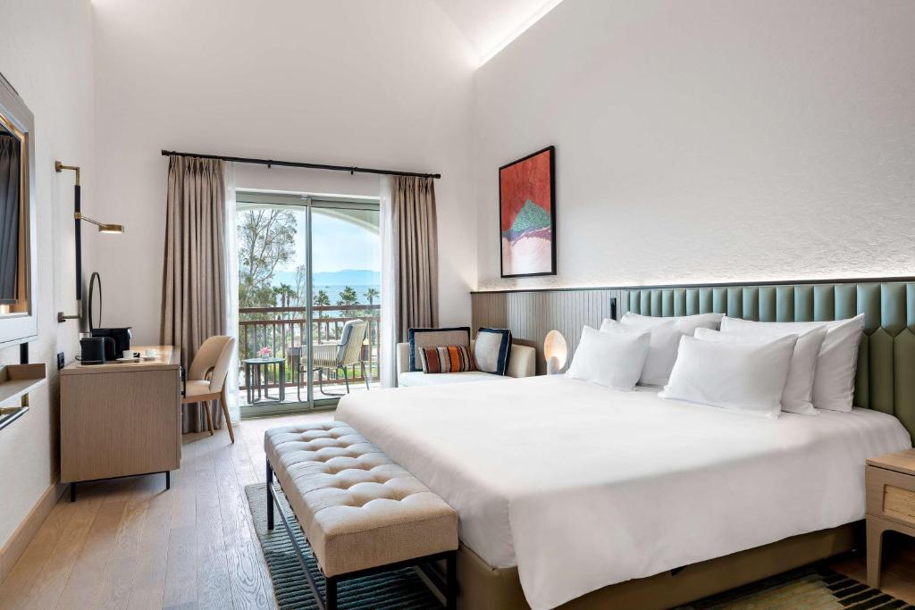 a bedroom with a large bed and a balcony at Radisson Collection Hotel, Bodrum in Akyarlar