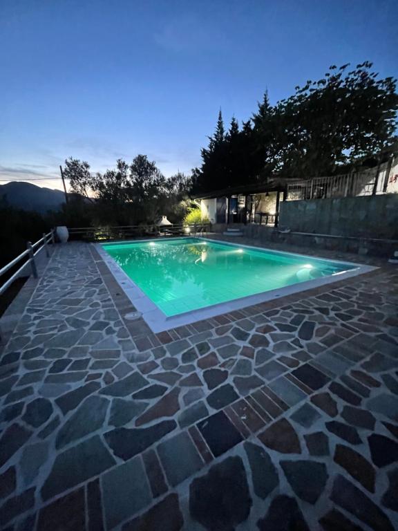 a swimming pool with a stone walkway around it at Villa Maroudia in Kymi