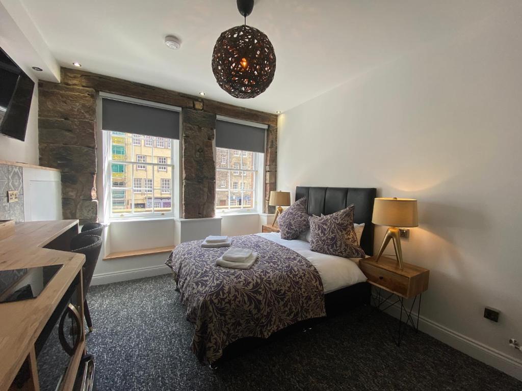 1 dormitorio con 1 cama y 2 ventanas en Royal Mile Romance by Heritage Of Scotland LLP en Edimburgo