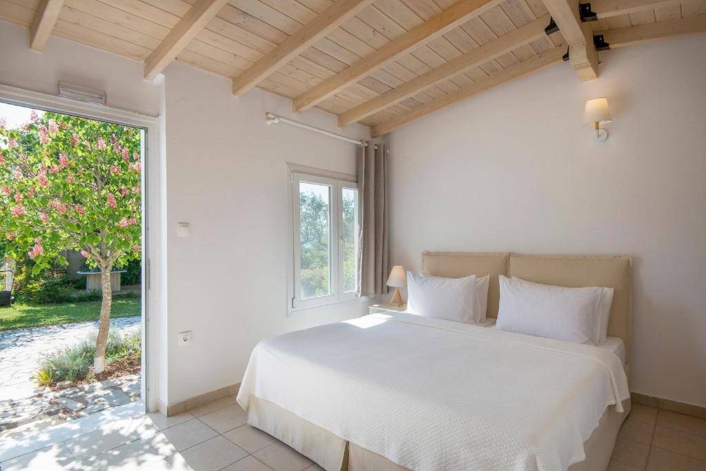 a bedroom with a white bed and a window at Sanidiamonds in Sani Beach