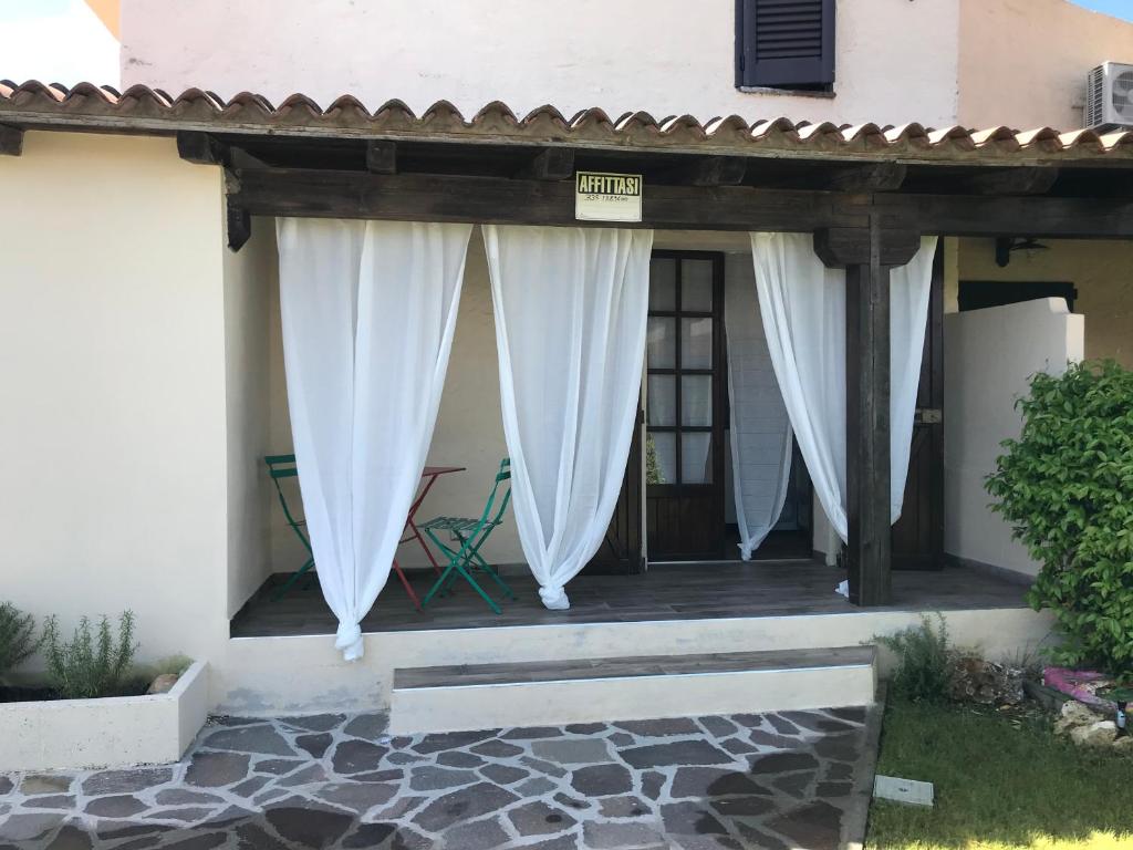 een veranda met witte gordijnen op een huis bij villetta san teodoro 7 posti IUN Q7135 in San Teodoro