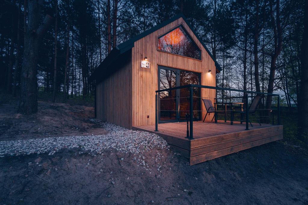 a small cabin with a deck in the woods at Harmony Place in Olsztyn