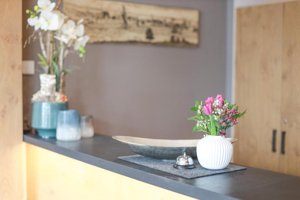 a counter with a sink and a vase with flowers on it at Hotel & Gasthof Wagner in Aichach