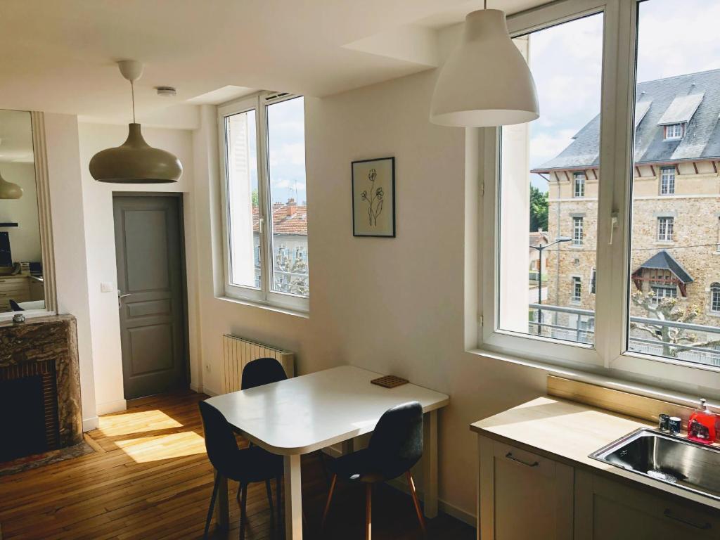 - une cuisine avec une table et deux chaises ainsi que deux fenêtres dans l'établissement Le seize, à Châlons-en-Champagne