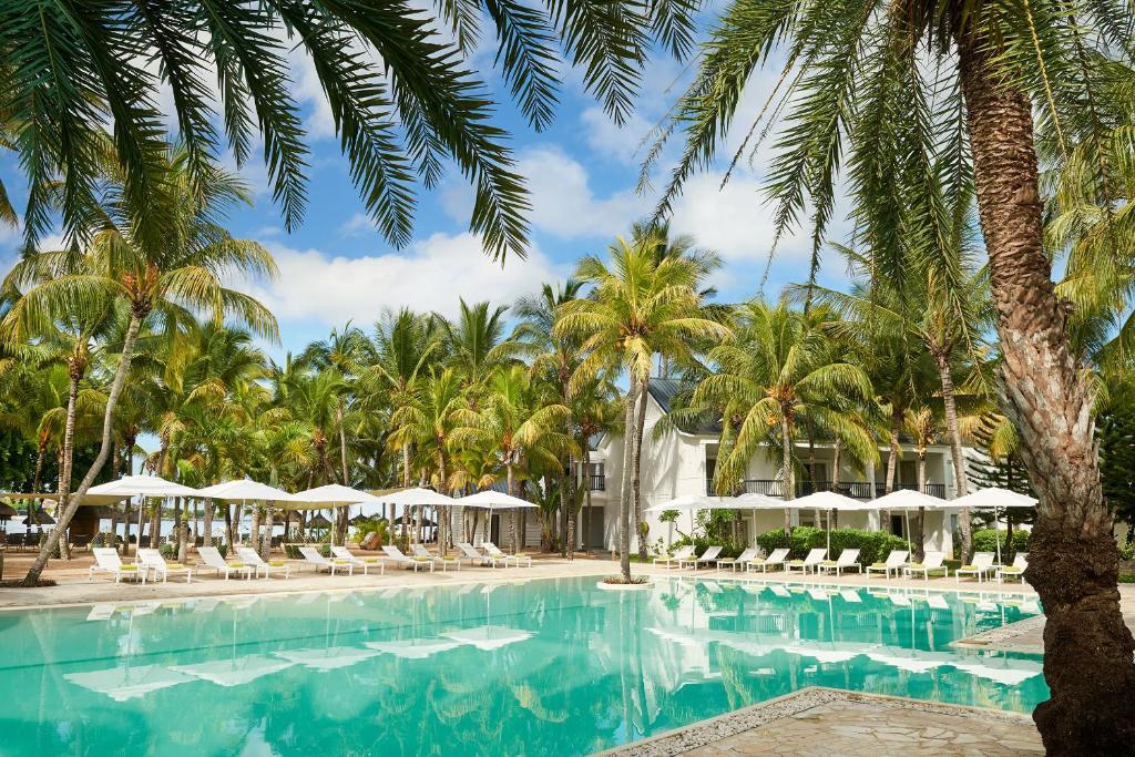 uma piscina no resort com palmeiras e guarda-sóis em The Ravenala Attitude em Balaclava