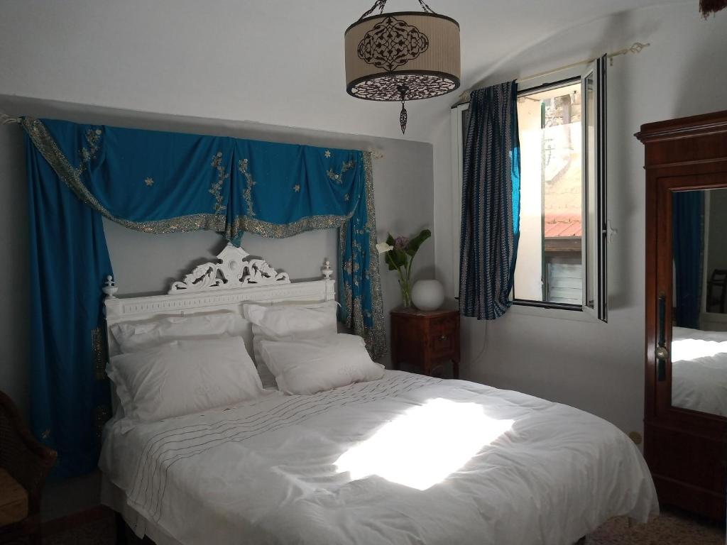 a bedroom with a white bed with a blue curtain at Holiday Home Carina in Dolceacqua