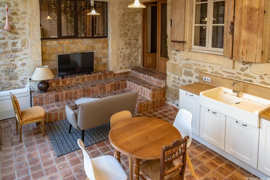 cocina con mesa y fregadero y TV en HANAËL, Gîte en maison d'hôtes, en Aubais
