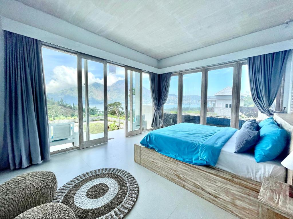 1 dormitorio con 1 cama y ventanas grandes en The Breezy Volcano, en Kintamani