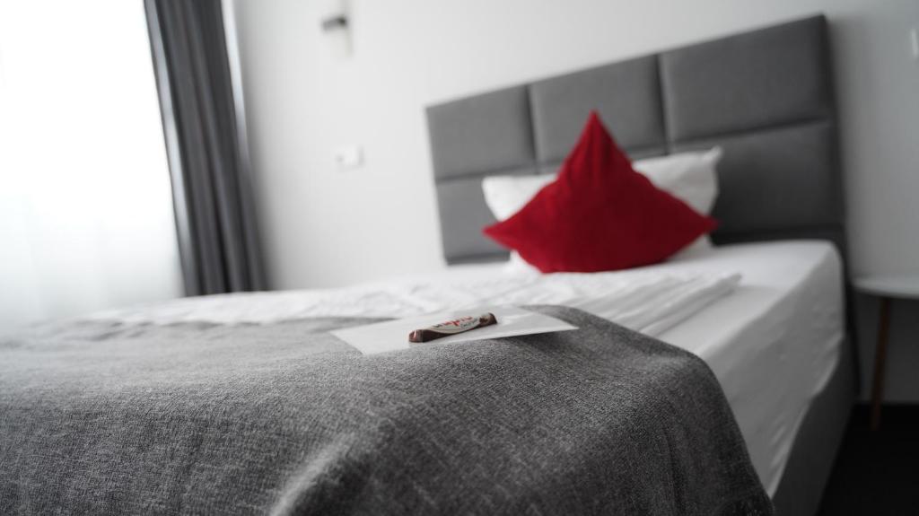 - une chambre avec un lit et un oreiller rouge dans l'établissement Amical Hotel Hagen - Am Hauptbahnhof, à Hagen