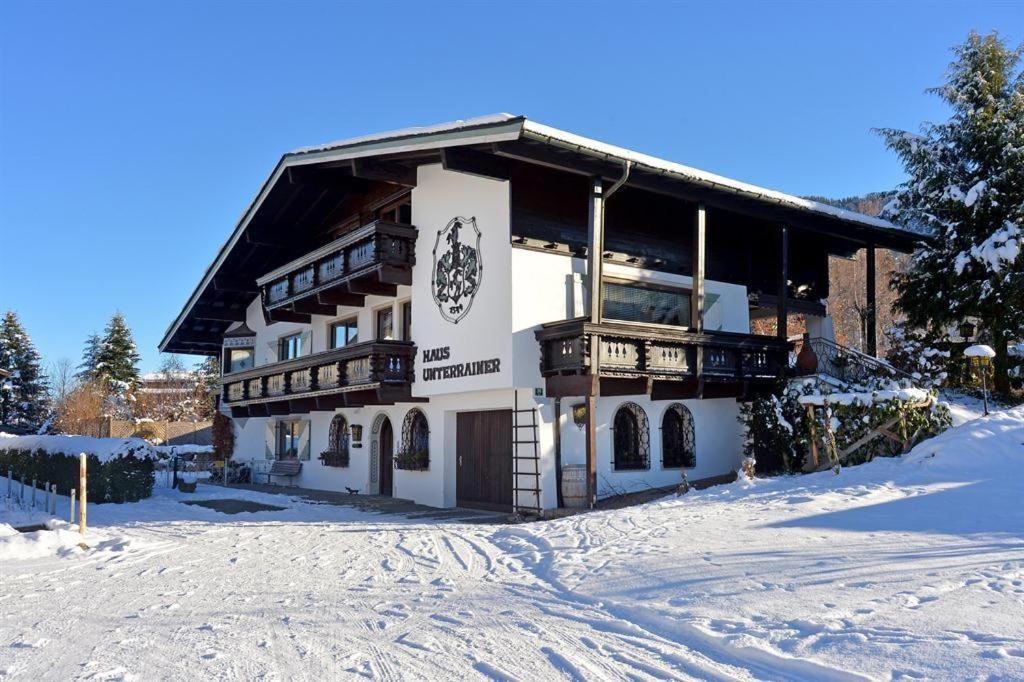 un grand bâtiment avec de la neige au sol dans l'établissement Alpenresidenz Unterrainer, à Ellmau