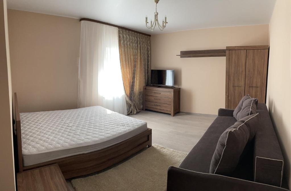 1 dormitorio con 1 cama y 1 sofá en Затишна однокімнатна квартира під Києвом, en Kopylov