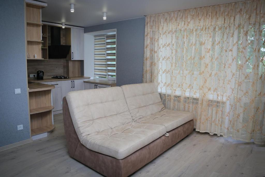Путивль Квартира студия في Putyvlʼ: أريكة بيضاء في غرفة معيشة مع مطبخ