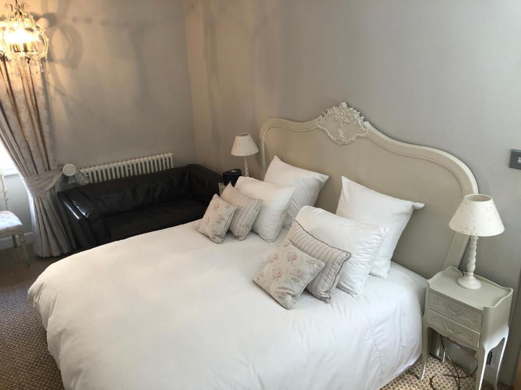 ein Schlafzimmer mit einem weißen Bett mit Kissen und einem Sofa in der Unterkunft St Martins Apartment Stamford in Stamford
